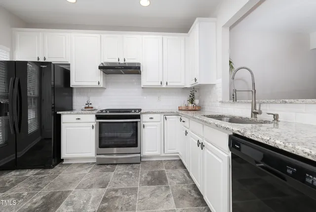 a kitchen with granite countertop a stove sink and refrigerator
