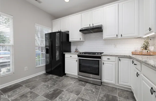 a kitchen with stainless steel appliances granite countertop a refrigerator stove and white cabinets