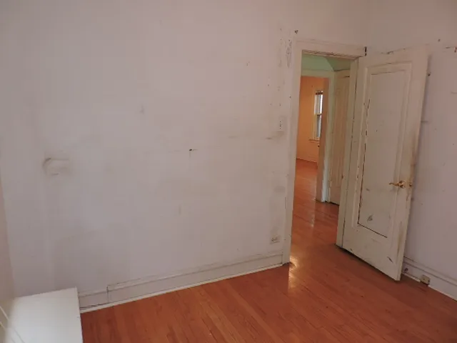 a view of an empty room with wooden floor and closet
