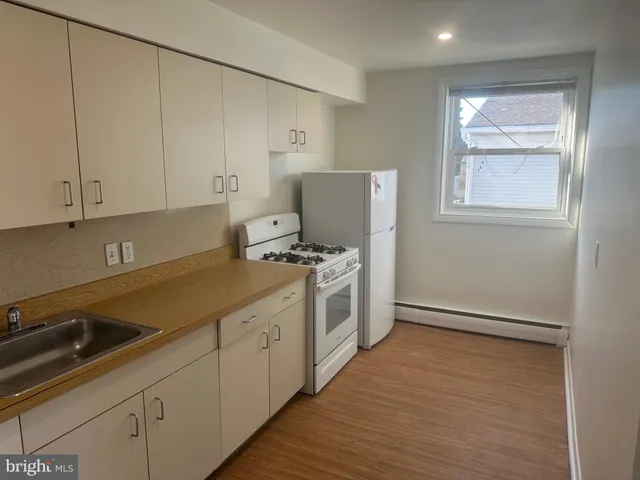 a kitchen with stainless steel appliances white cabinets and wooden floors