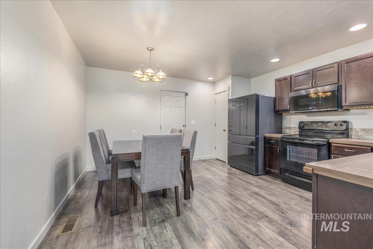 661 North Scotney Avenue Meridian, ID 83642 - Photo 11 of 22 Kitchen featuring dark brown cabinetry, stainless steel appliances, light countertops, recessed lighting, and decorative light fixtures
