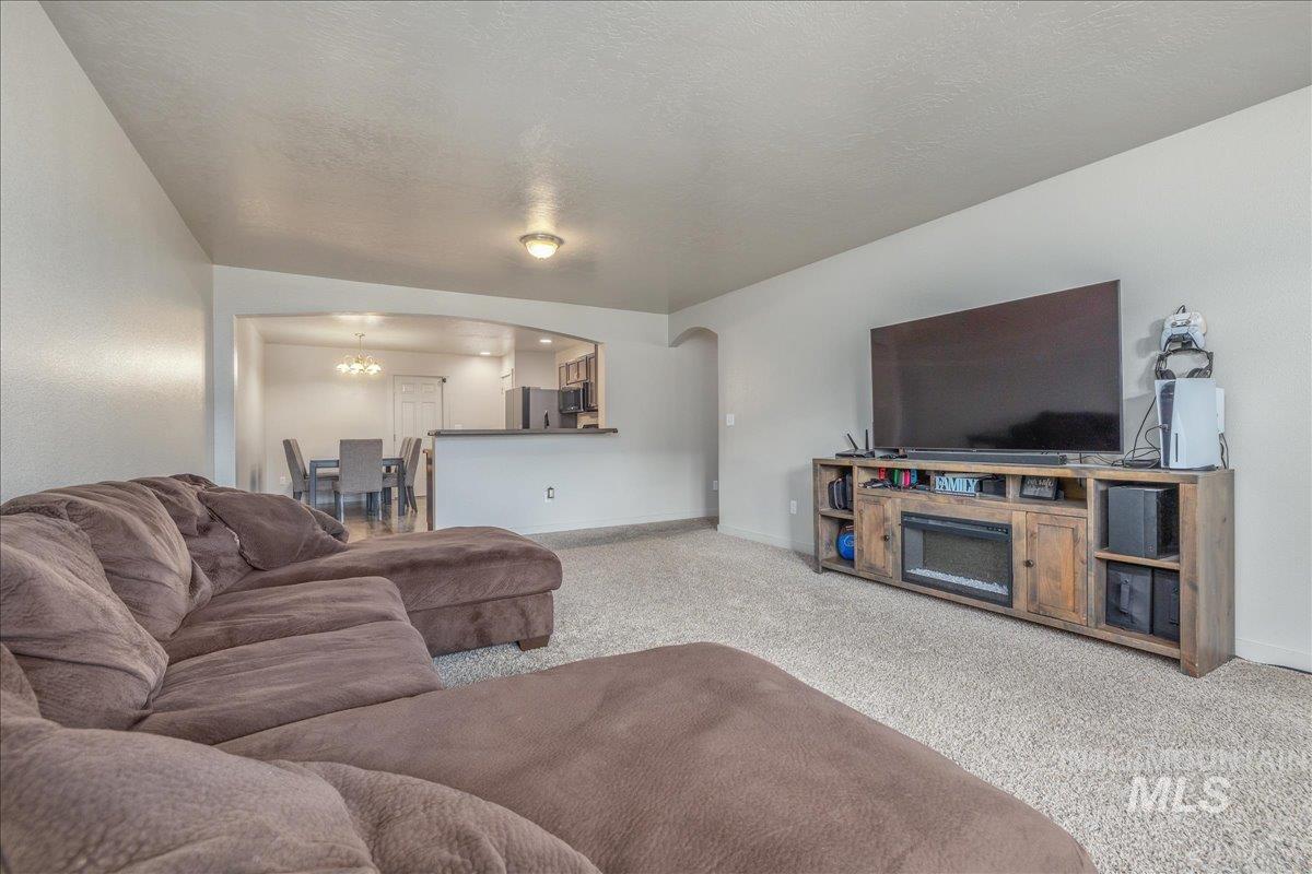 661 North Scotney Avenue Meridian, ID 83642 - Photo 4 of 22 Living area with arched walkways, a chandelier, carpet flooring, and a textured ceiling