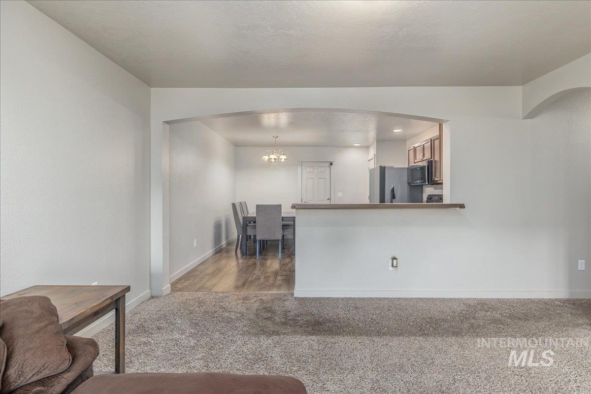 661 North Scotney Avenue Meridian, ID 83642 - Photo 6 of 22 Living room with light colored carpet, arched walkways, a chandelier, a textured ceiling, and recessed lighting