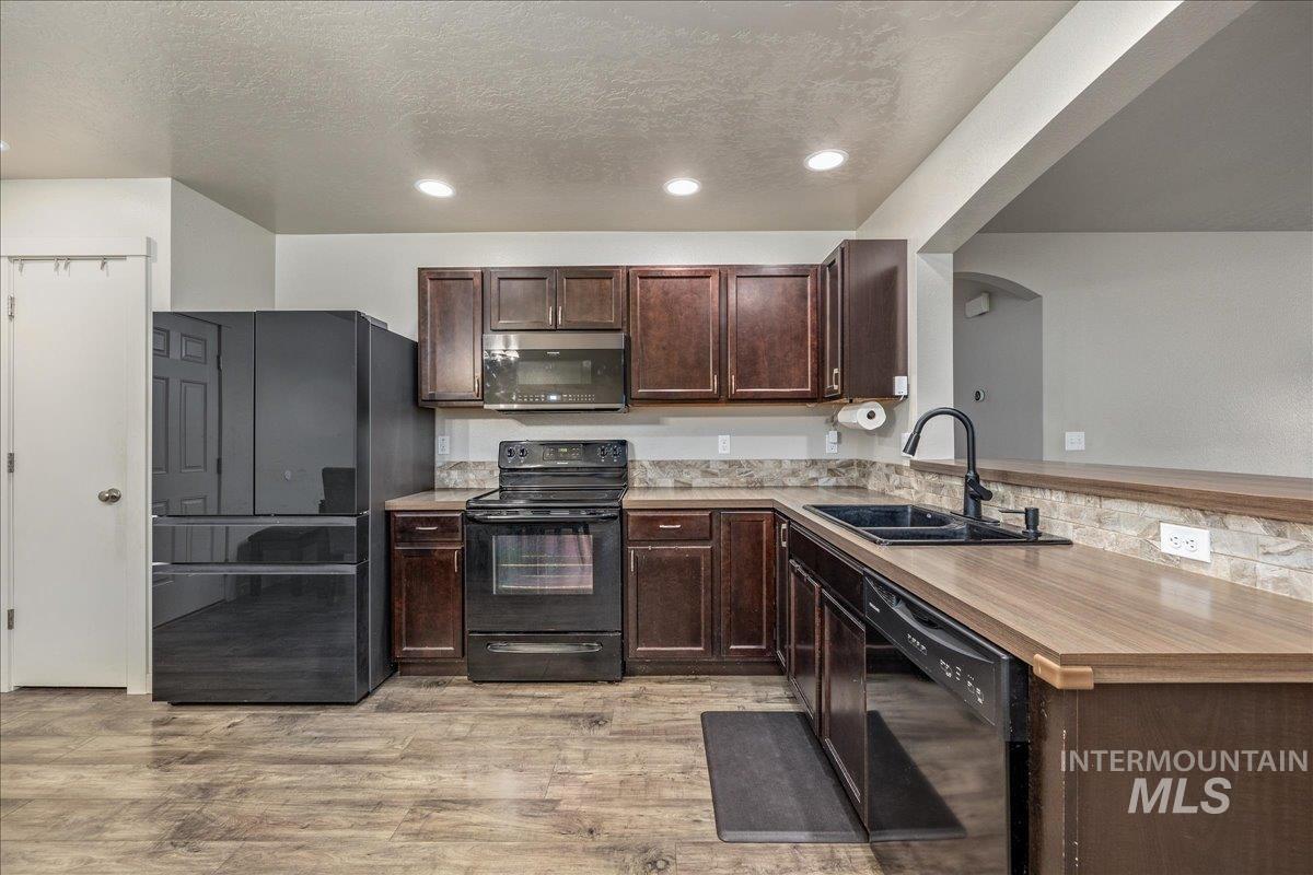 661 North Scotney Avenue Meridian, ID 83642 - Photo 8 of 22 Kitchen featuring black appliances, dark brown cabinetry, light countertops, recessed lighting, and a textured ceiling
