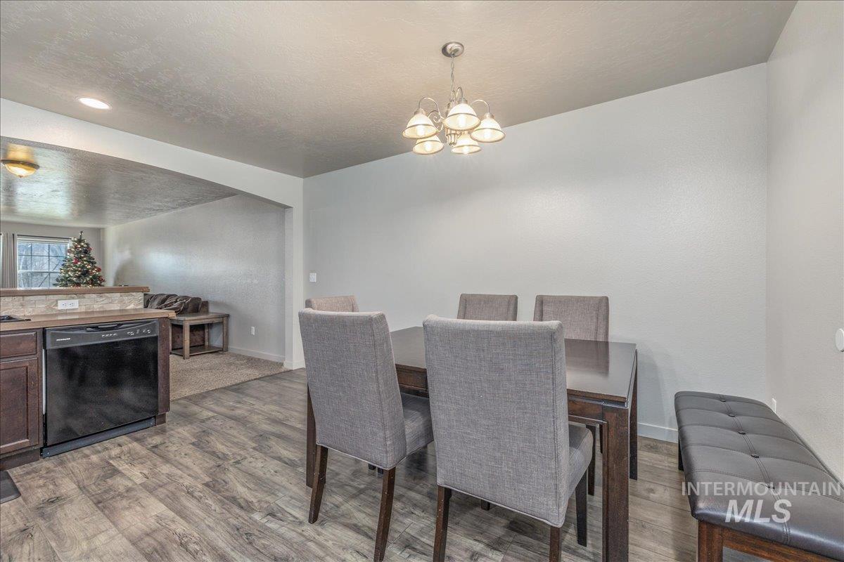 661 North Scotney Avenue Meridian, ID 83642 - Photo 9 of 22 Dining room with a textured ceiling, light wood-style flooring, a chandelier, and arched walkways
