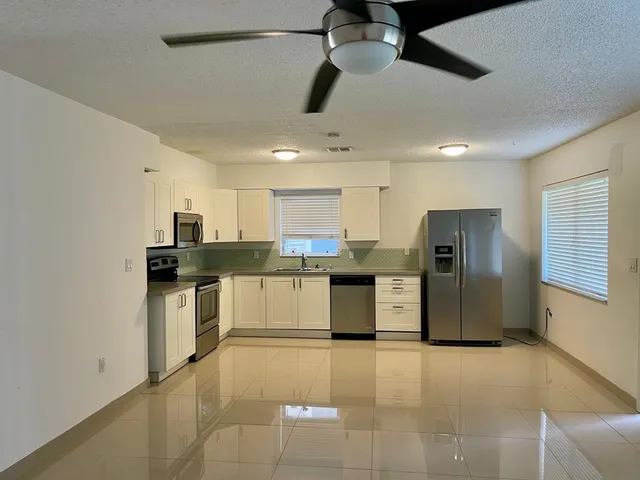 a large kitchen with stainless steel appliances kitchen island a refrigerator sink and cabinets