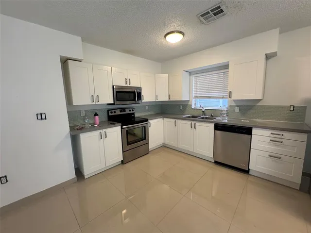 a kitchen with granite countertop white cabinets and white appliances