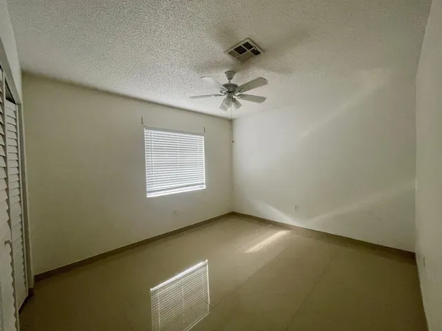 an empty room with a window and a ceiling fan