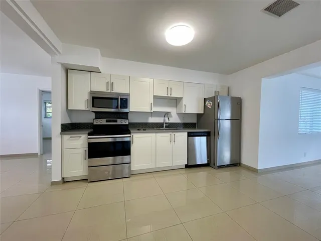 a kitchen with stainless steel appliances a refrigerator sink and white cabinets