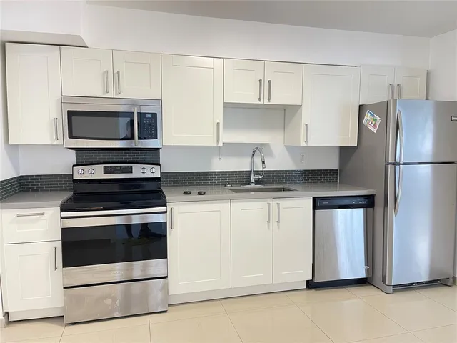 a kitchen with granite countertop white cabinets and white stainless steel appliances