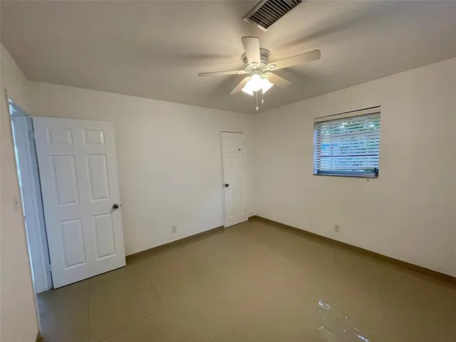 an empty room with a chandelier fan and windows