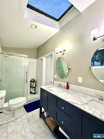 a bathroom with a granite countertop sink mirror vanity and toilet