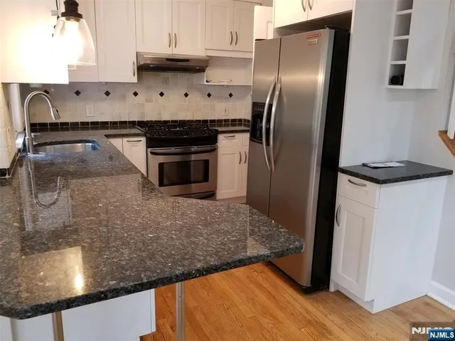 a kitchen with stainless steel appliances granite countertop a refrigerator and a stove