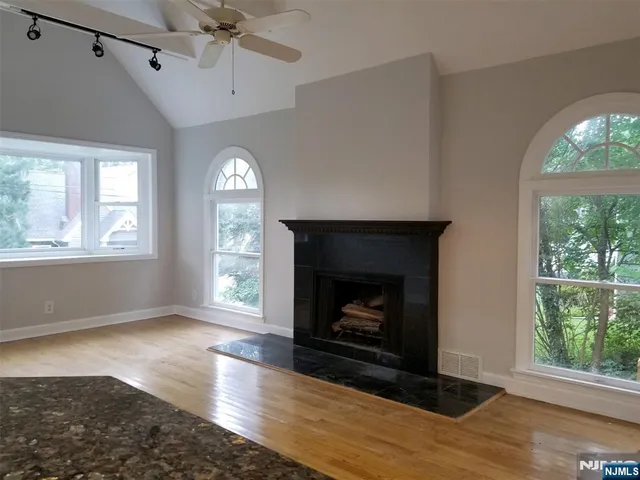 a living room with a fireplace with wooden floor a fireplace and a window