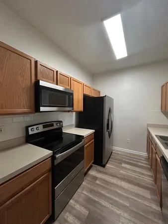 a kitchen with granite countertop a refrigerator and a stove top oven