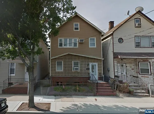 a front view of a house with a tree
