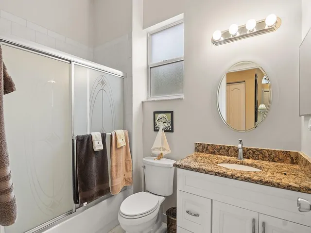 a bathroom with a granite countertop sink toilet and shower