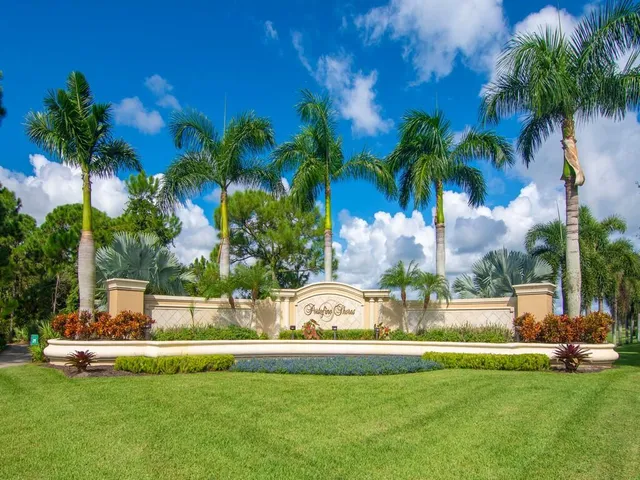 a view of a fountain in front of house with palm trees