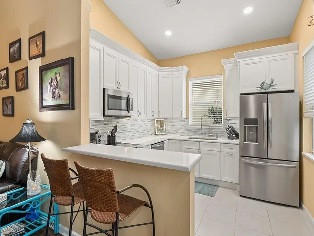 a kitchen with stainless steel appliances granite countertop a dining table chairs refrigerator and sink