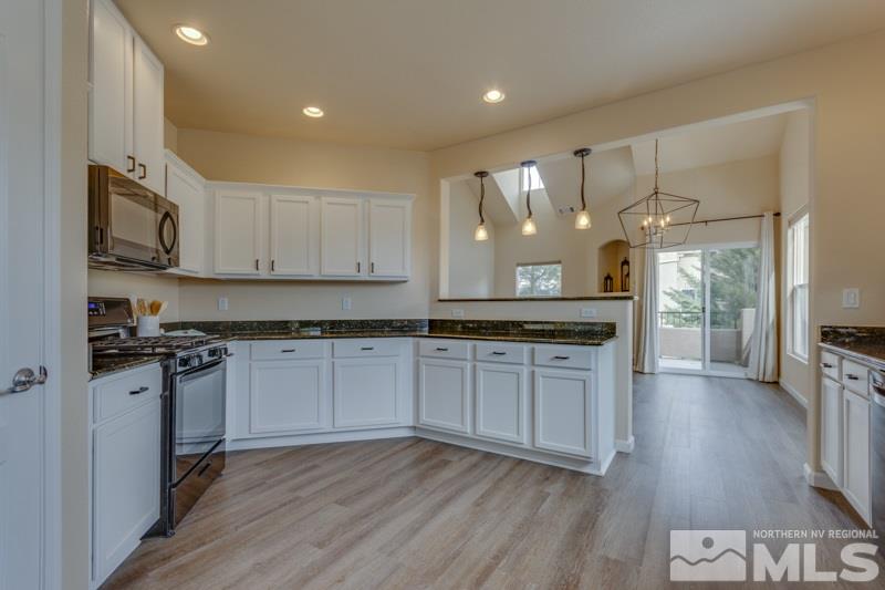 9050 Double R Boulevard, Unit 724 Reno, NV 89511 - Photo 5 of 18 a kitchen with stainless steel appliances granite countertop wooden cabinets a sink a stove a dining table and chairs