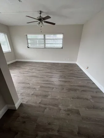 en empty room with wooden floor and ceiling fan