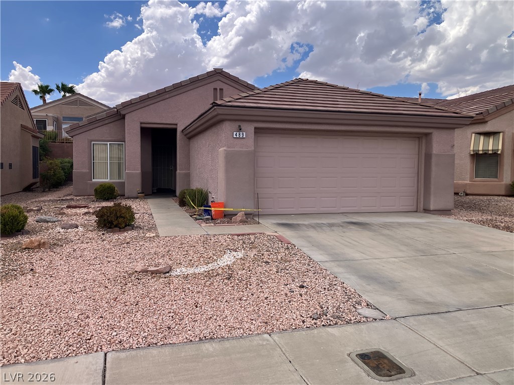 A classic stucco exterior features a tile roof and a spacious concrete driveway.