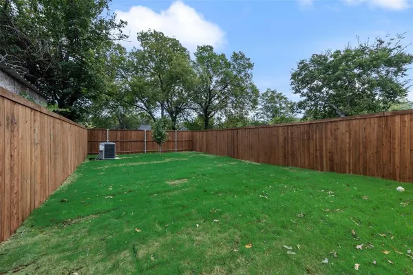 a view of a backyard with large trees and wooden fence