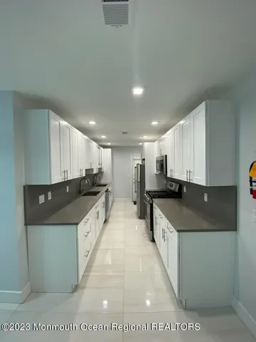 a large kitchen with stainless steel appliances kitchen island a large counter top a stove and a sink