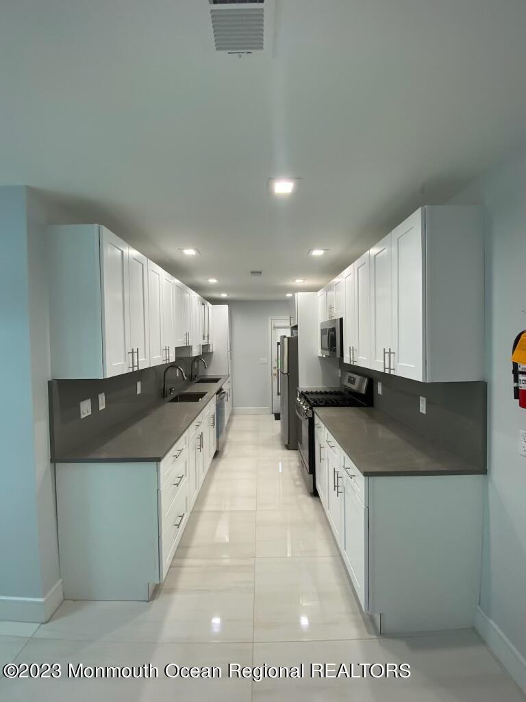 258 Norgrove Avenue Long Branch, NJ 07740 - Photo 14 of 16 a large kitchen with stainless steel appliances kitchen island a large counter top a stove and a sink