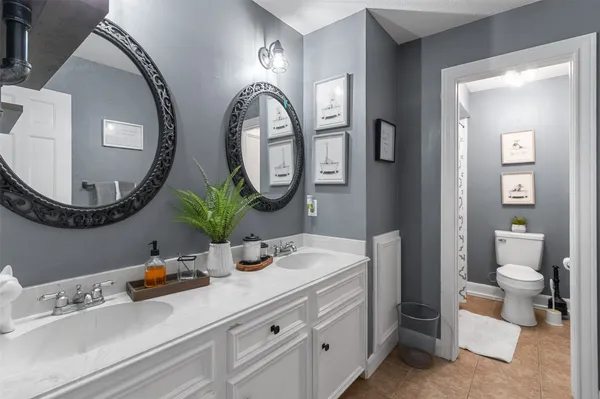 a bedroom with a bed lamp and paintings on the wall