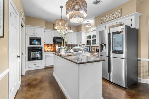 a kitchen with stainless steel appliances granite countertop a refrigerator and a stove top oven
