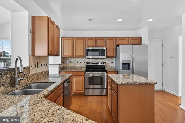 a kitchen with granite countertop a sink stove and refrigerator
