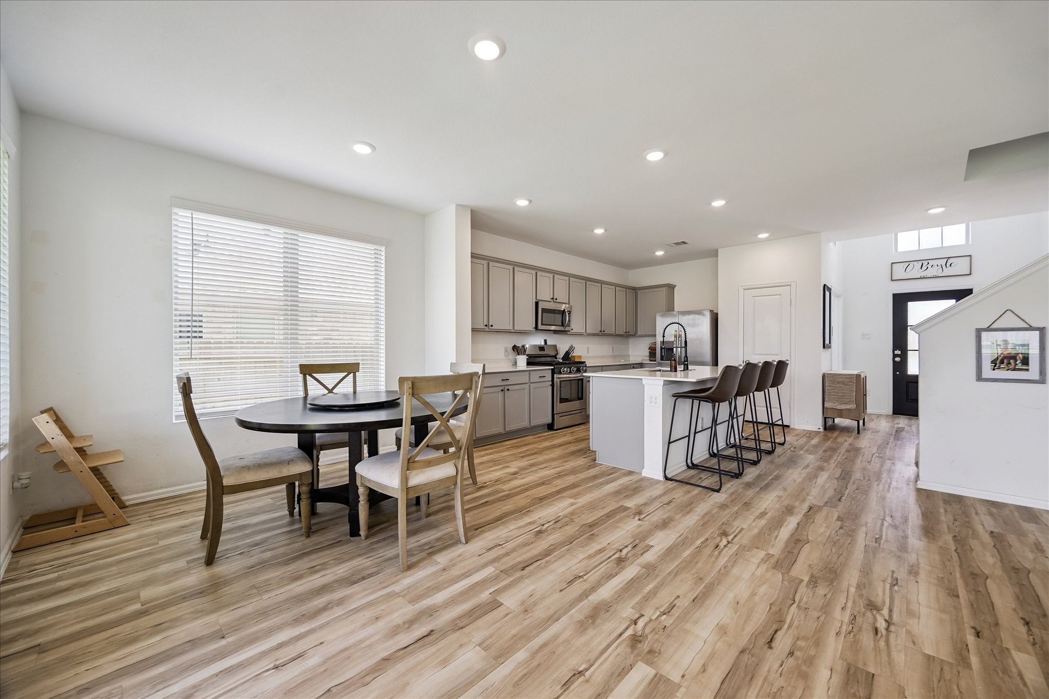 3812 Moss Hl Road Rosenberg, TX 77469 - Photo 11 of 20 This photo showcases a bright, open-concept kitchen and dining area with modern finishes. The kitchen features sleek cabinetry, stainless steel appliances, and a spacious island with bar seating. The dining area is adjacent, with large windows providing ample natural light.