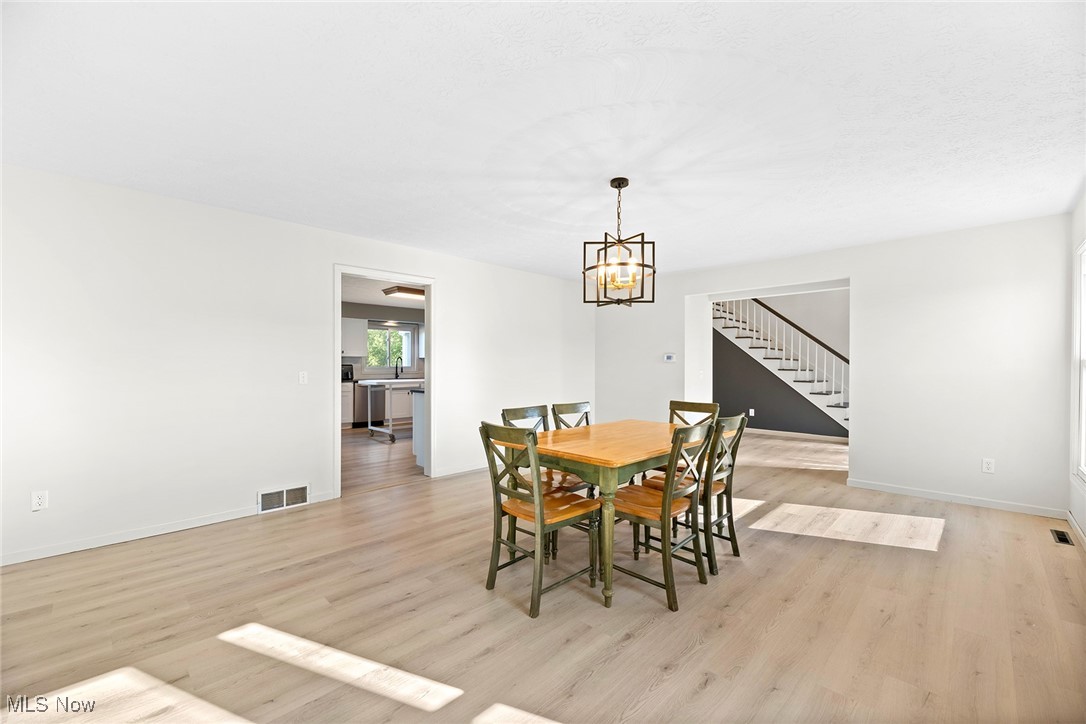 2236 Hartville Road Mogadore, OH 44260 - Photo 13 of 50 Dining area featuring light wood-type flooring, stairway, and a chandelier