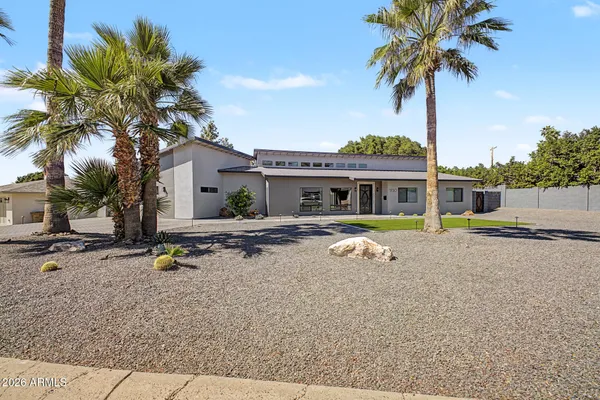 a palm tree sitting in front of a house with a yard