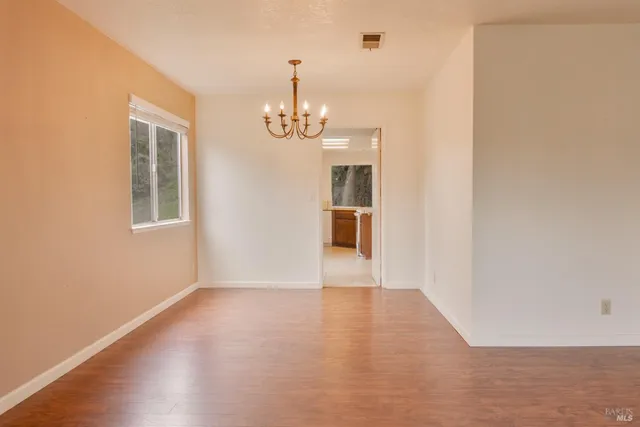 a view of a room with wooden floor kitchen and windows