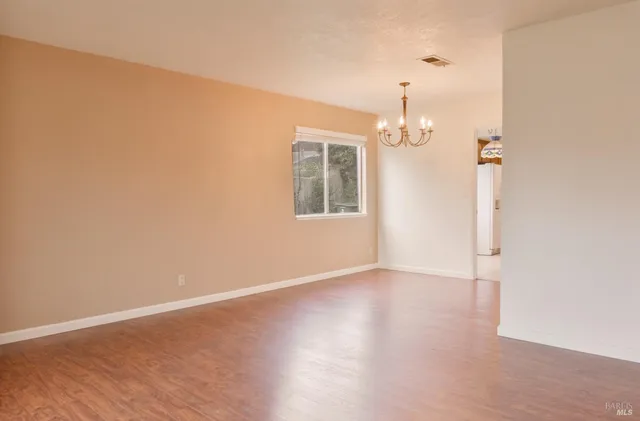 an empty room with wooden floor cabinet and windows