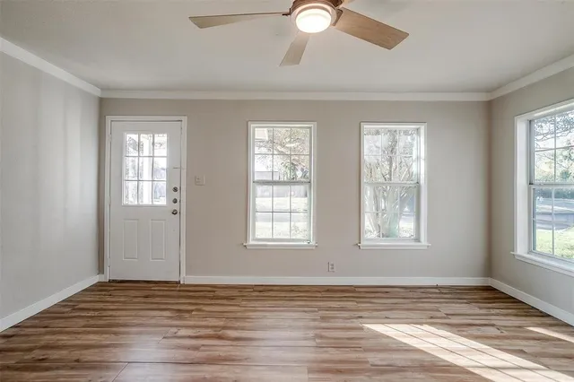 a view of an empty room with wooden floor and window