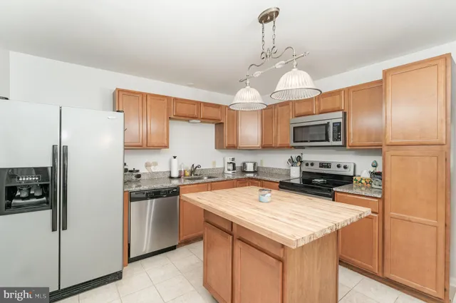 a kitchen with kitchen island granite countertop stainless steel appliances cabinets a sink and a counter top space