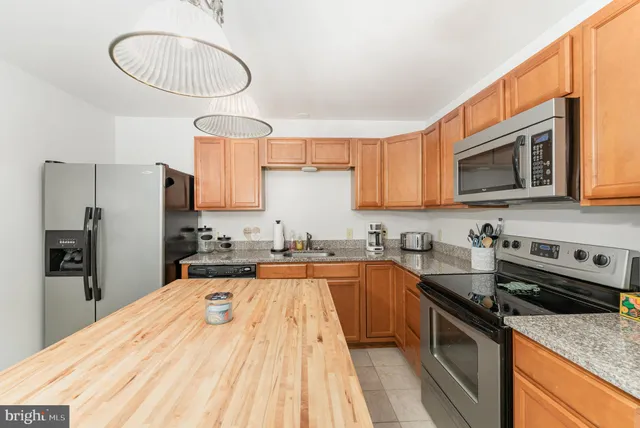 a kitchen with stainless steel appliances granite countertop a sink dishwasher stove and refrigerator with wooden floor