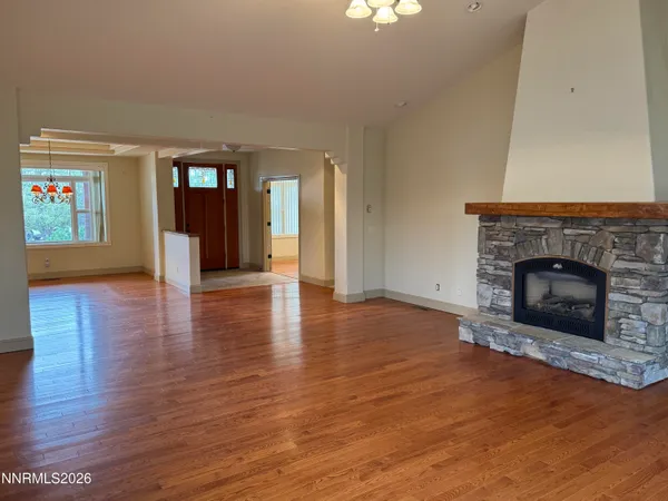 a view of an empty room with wooden floor fireplace and a window