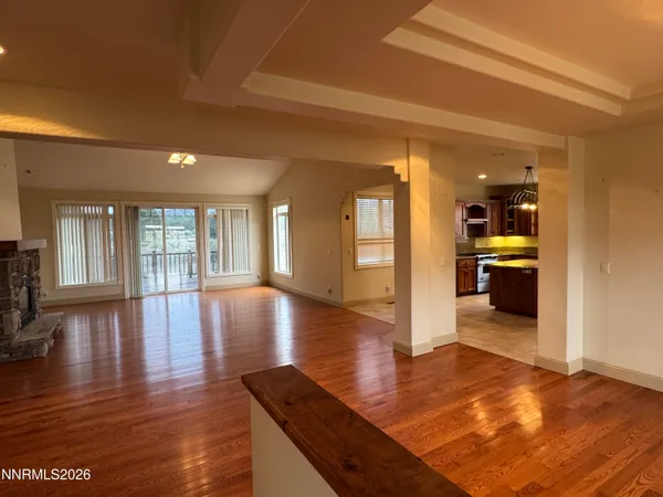 a view of a hallway with wooden floor and a kitchen