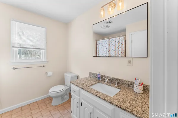 a bathroom with a granite countertop sink toilet and mirror