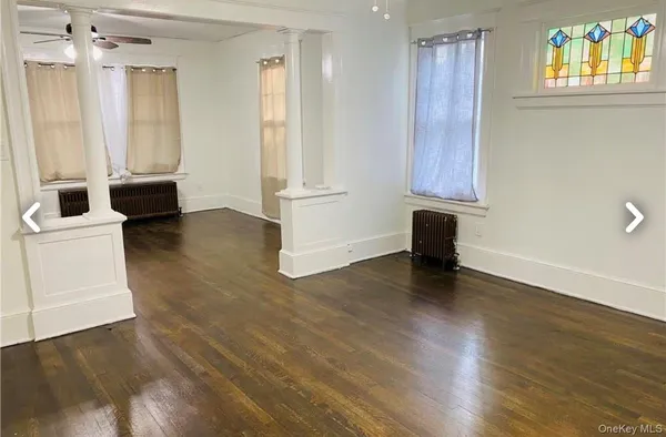 a view of an empty room with a window and wooden floor