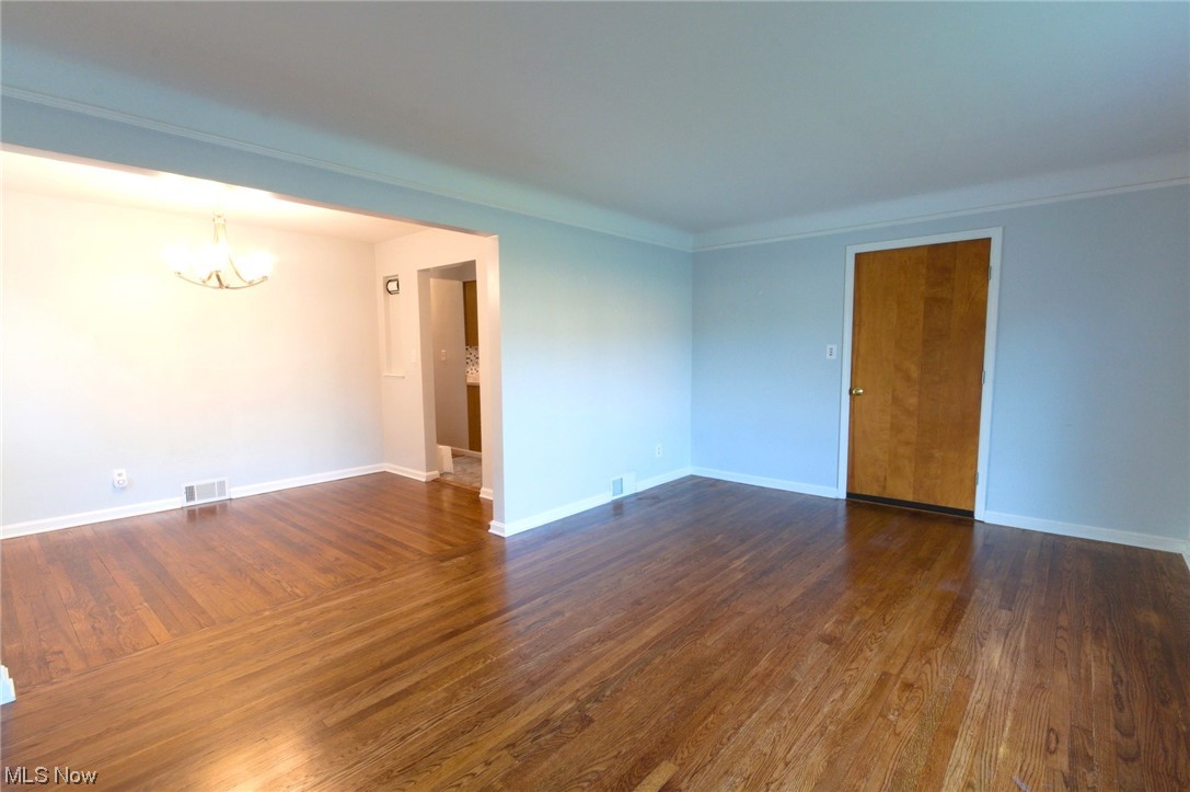 6462 Ridge Road Parma, OH 44129 - Photo 11 of 24 Spare room featuring ornamental molding, an inviting chandelier, and dark wood-type flooring