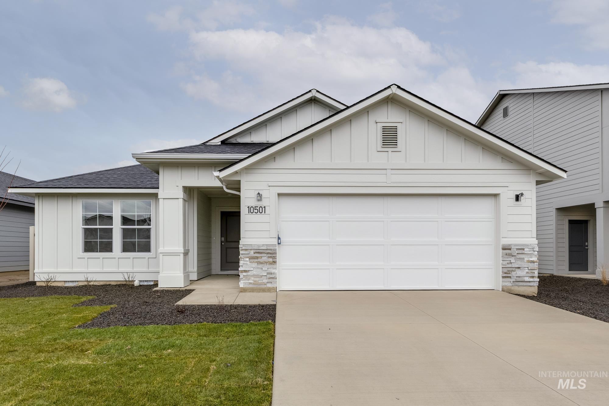 View of front of house featuring board and batten siding, roof with shingles, stone siding, and driveway
