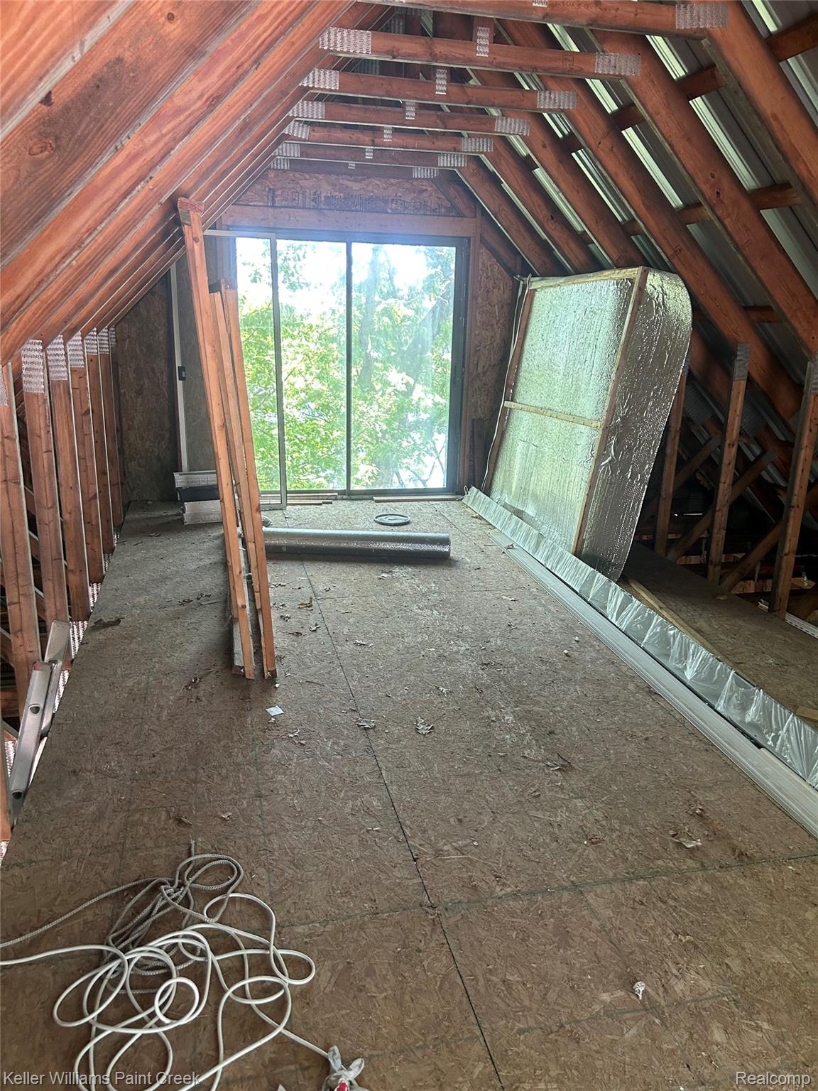 227 Ora Road Oxford, MI 48371 - Photo 57 of 60 Spacious attic space featuring exposed wood rafter beams, oriented strand board flooring, and a large sliding glass door