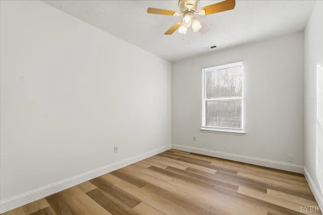 an empty room with a window and a fan