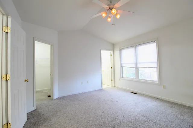 an empty room with windows and chandelier fan