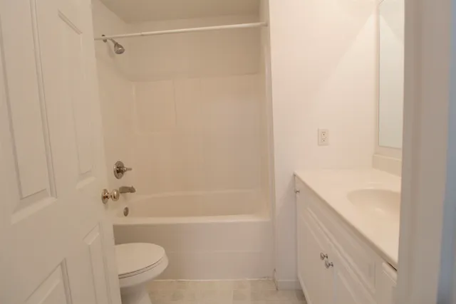 a bathroom with a granite countertop bathtub shower sink vanity and toilet